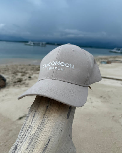 Baseballkeps i bomull med elfenbensvit Cocomoon Sweden brodyr framtill. Denna keps har unisex storlek.