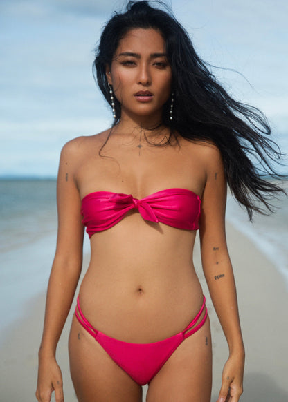 Stella top, en rosaskimrande bandeau bikini med en löstagbar rosett. Nova i skimrande Raspberry Pink är en trendig och feminin bikinitrosa med låg midja och brasiliansk skärning, perfekt för dig som vill ha en solig, minimalistisk bikini som verkligen syns. Underdelen är vändbar, har dubbla smala snören i sidorna och ger en stilren, lätt och modern look på stranden.
Exklusiva badkläder från Cocomoon Sweden.