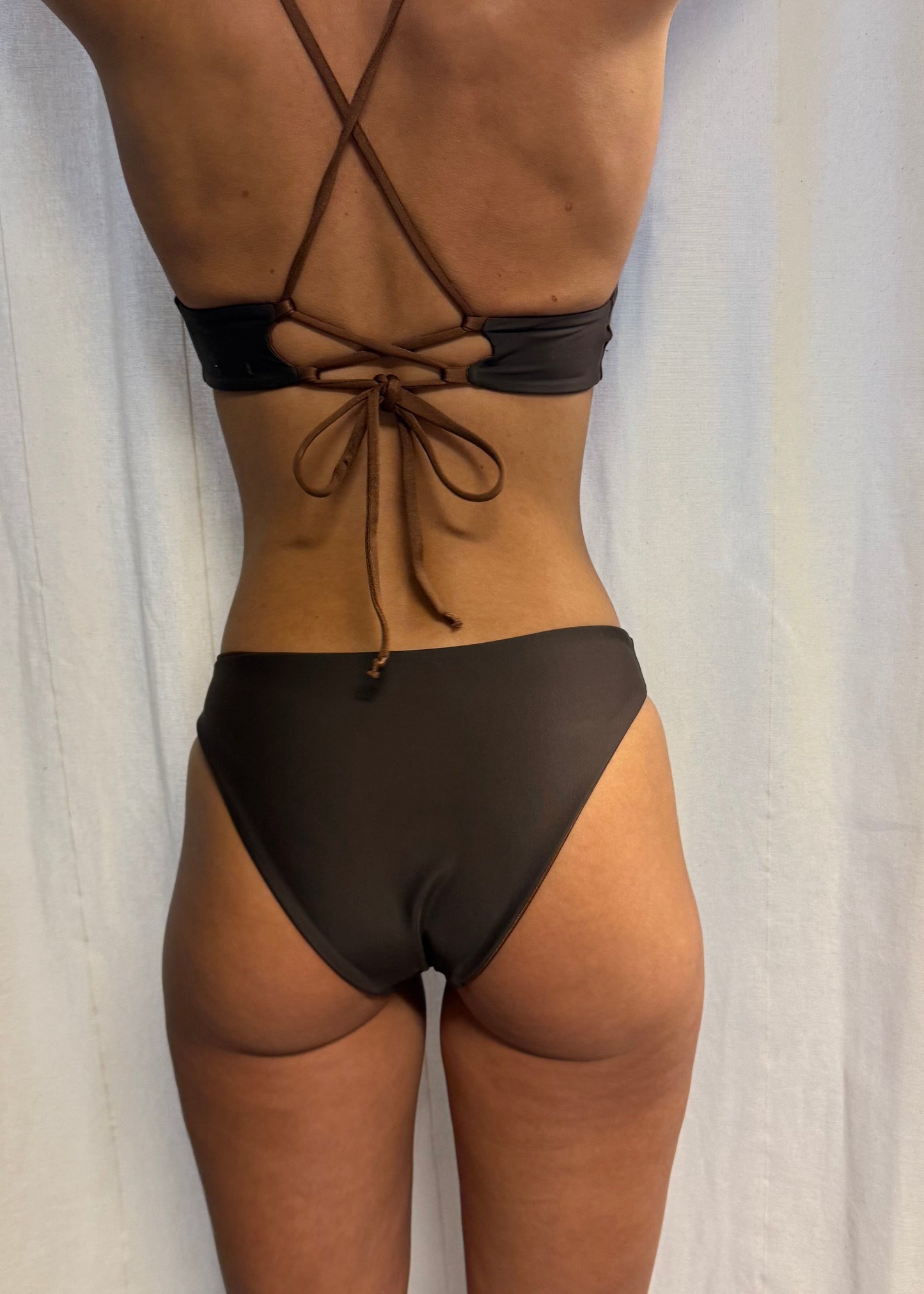 Ebba Bottom Chocolate är en chokladbrun bikinitrosa i briefmodell med normal midja och en något högre skärning framtill som ger ett visuellt intryck av längre ben. Underdelen är vändbar där ena sidan har en varmare brun ton med subtil lyster, medan den andra sidan är mörkbrun med sammetslen känsla. Bikiniunderdelen har medium täckning baktill. Stylad med Daniela Top, en  sportig bikinitopp med feminina detaljer och justerba snörning i ryggen. Svenska premium badkläder från Cocomoon Sweden.