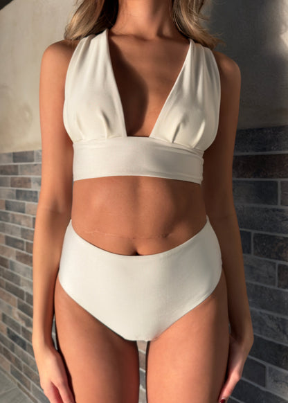 Sarah top, är en elegant bikinitopp i en skimrande elfenbensvit. En vacker djup V-ringning framtill, breda sköna axelband och en innovativ snörning i ryggen gör att den sitter som en smäck. Svenska premiumbadkläder för dam, Cocomoon Sweden. 